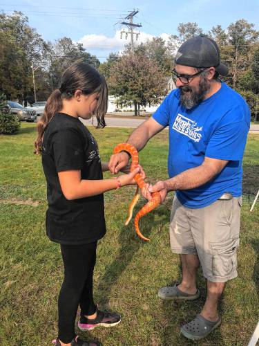 Nate Monty of Morphs and Milestones introduces Cheeto, a corn snake, to a young visitor from Deering.